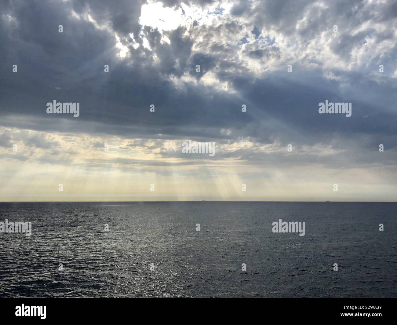 Sunlight shining through clouds over sea - Smartphone Captured Stock Image