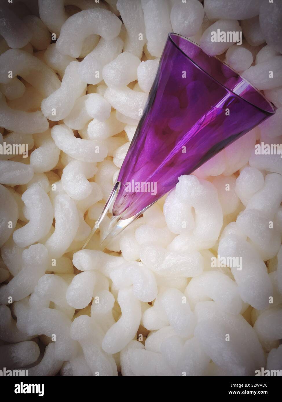 Fragile amethyst colored crystal champagne flute in a cardboard packing box surrounded by Styrofoam peanuts - Smartphone Captured Stock Image