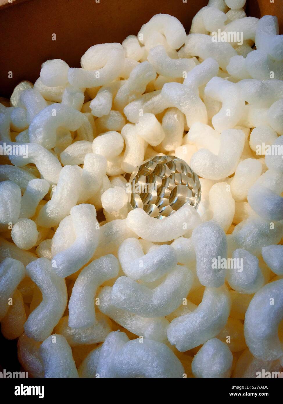 Fragile crystal decanter stopper in a cardboard packing box surrounded by Styrofoam peanuts - Smartphone Captured Stock Image