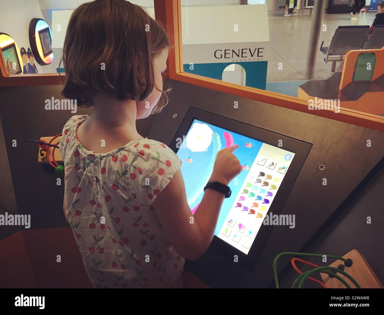 7 / Seven year old girl / child plays in control tower in the kids area of Geneva international airport / Geneve air port / aeroport. The girl is model released but people in background are not. - Smartphone Captured Stock Image