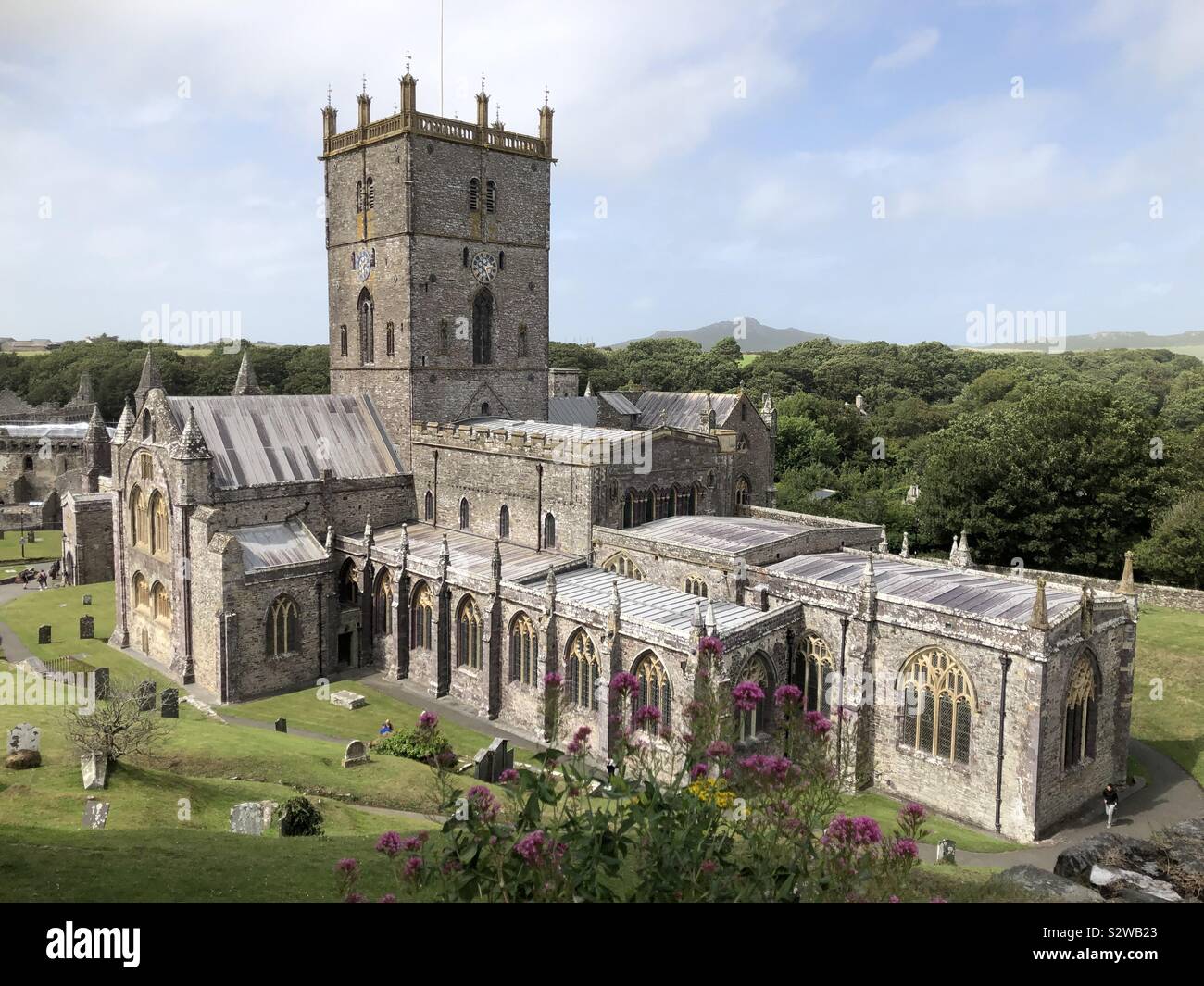 Saint David’s Cathedral, St David’s, Pembrokeshire, Wales with beautiful coastal landscape behind. Stock Photo