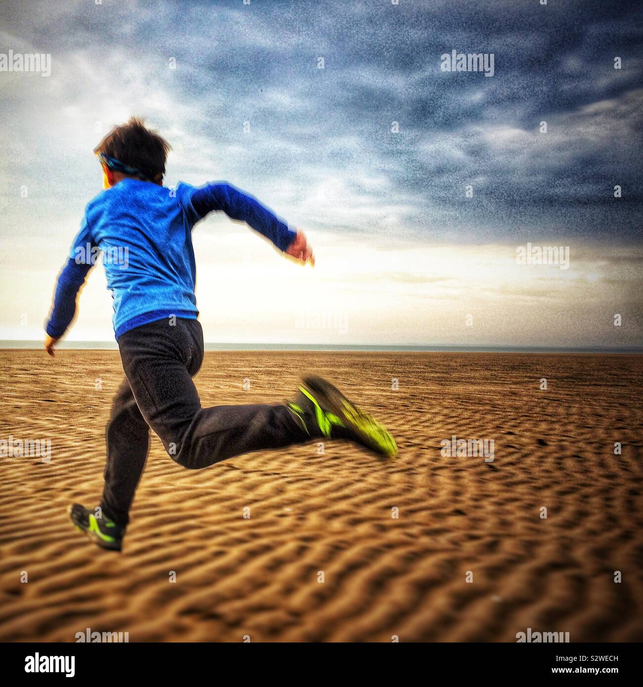 Boy running on the dunes beach in U.K. Stock Photo