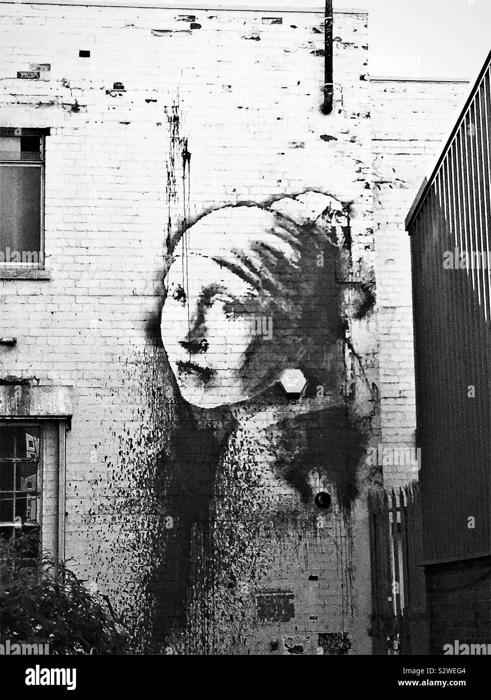 Black and white picture of ‘Girl with a Pierced Eardrum’ street art by Banksy, near Bristol harbour, UK Stock Photo