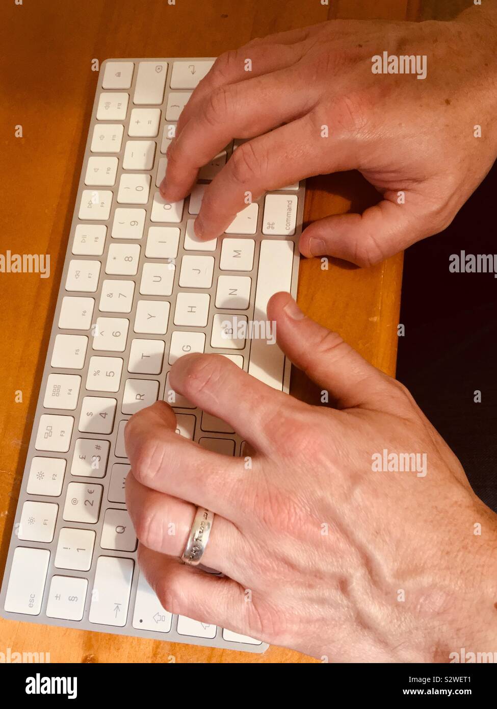 Man typing on wireless keyboard at office desk Stock Photo