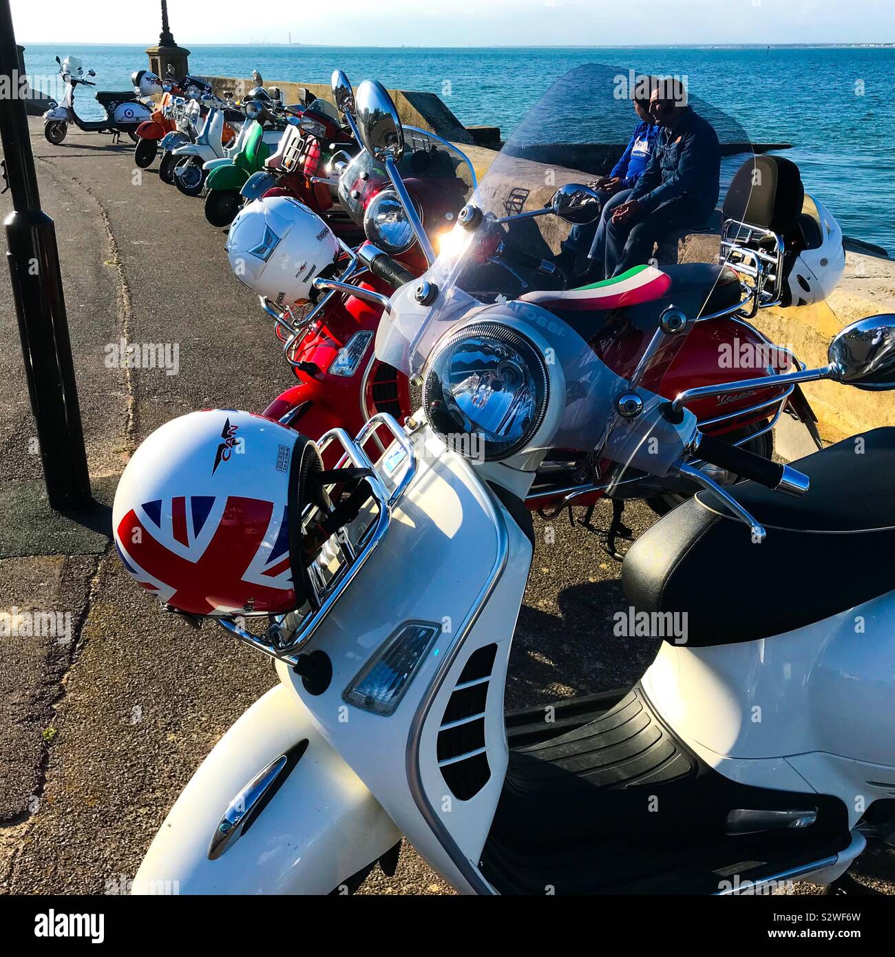 A row of scooters parked up at the seaside on the seafront at the annual scooter rally at Ryde on the Isle of Wight Stock Photo