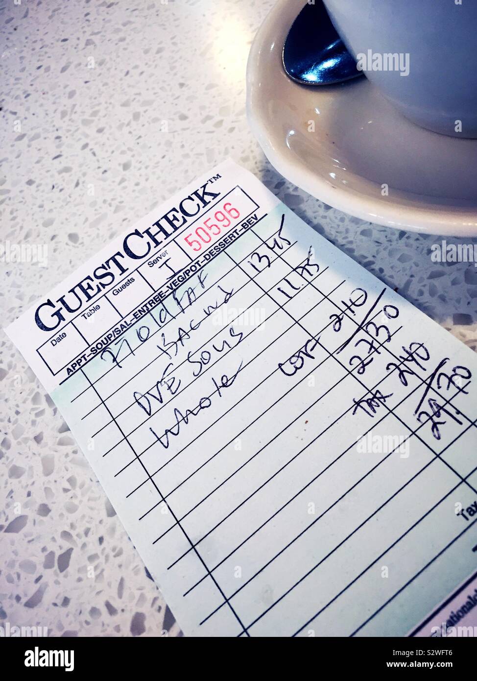 Diner breakfast check next to coffee cup and saucer, USA - Smartphone Captured Stock Image