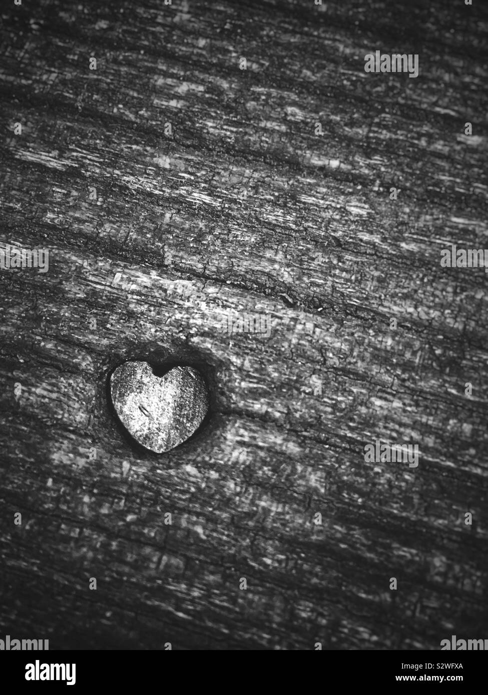 Black and white photo of a carved heart on a wooden table. top. Copy space for text. - Smartphone Captured Stock Image