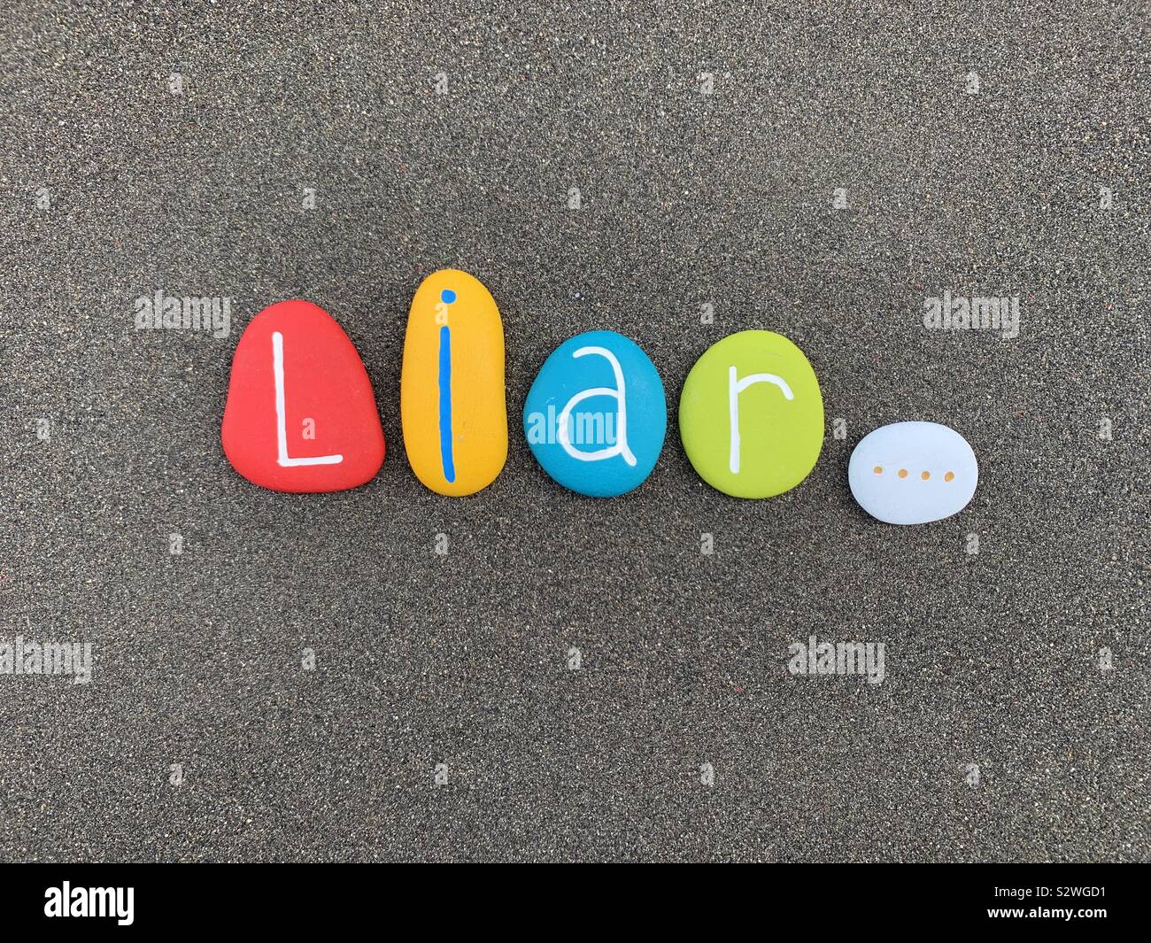 Liar, english word composed with colored stones over black volcanic sand Stock Photo