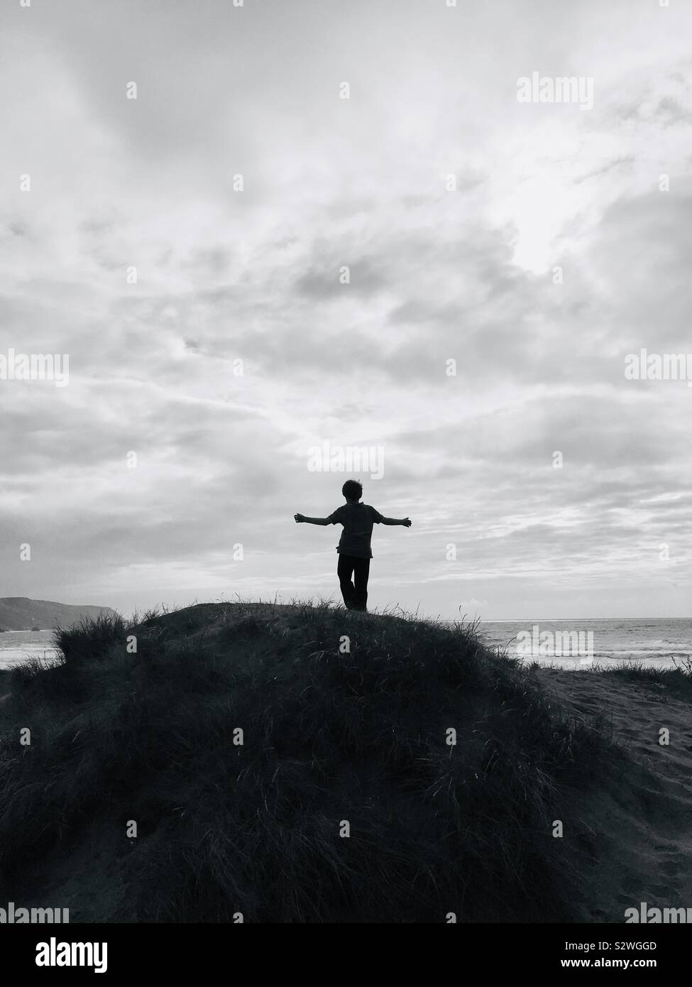 Boy looking out to sea on a sand dune Cornwall UK Stock Photo