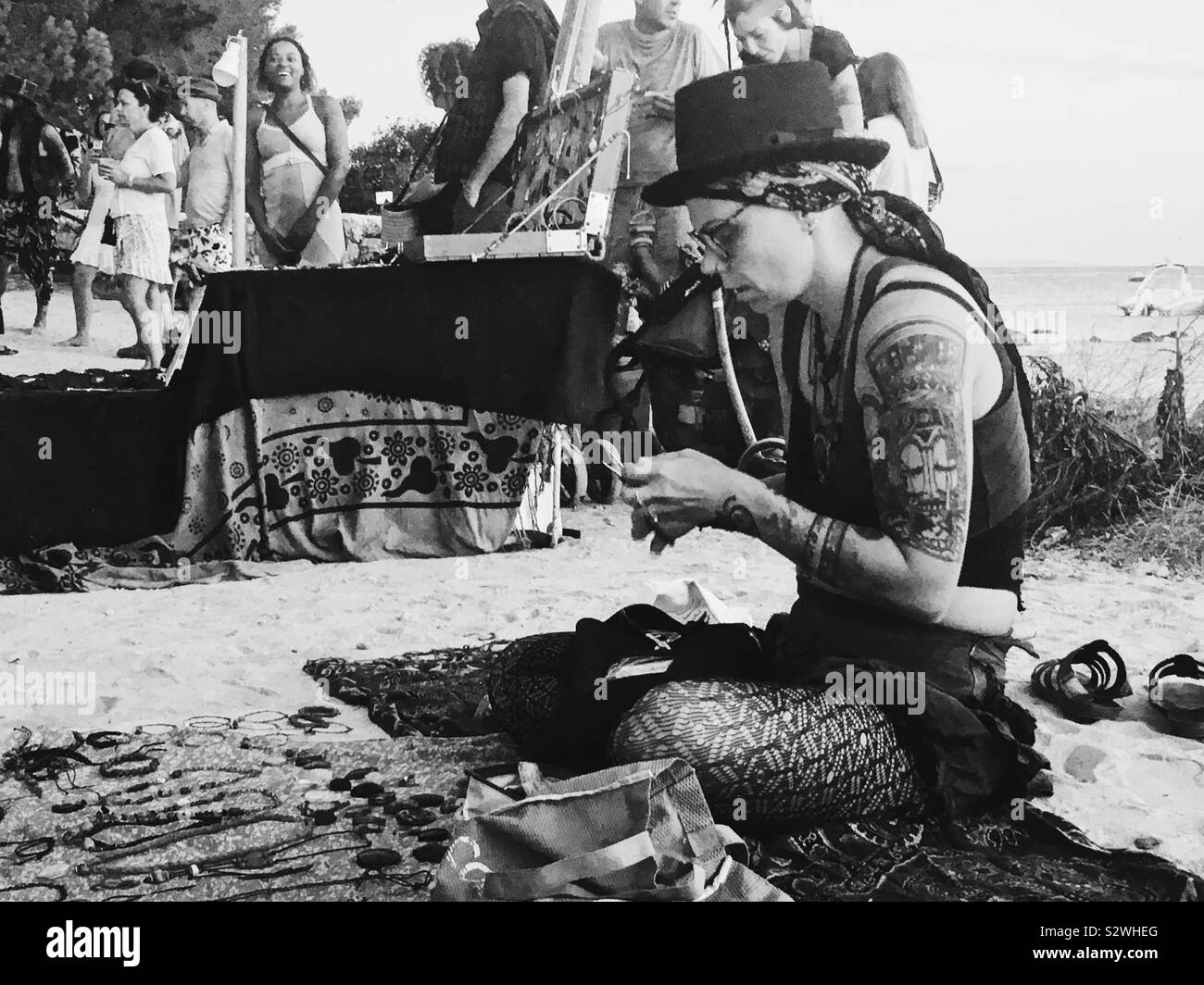 Hippy in Ibiza making Jewellery on beach - Smartphone Captured Stock Image