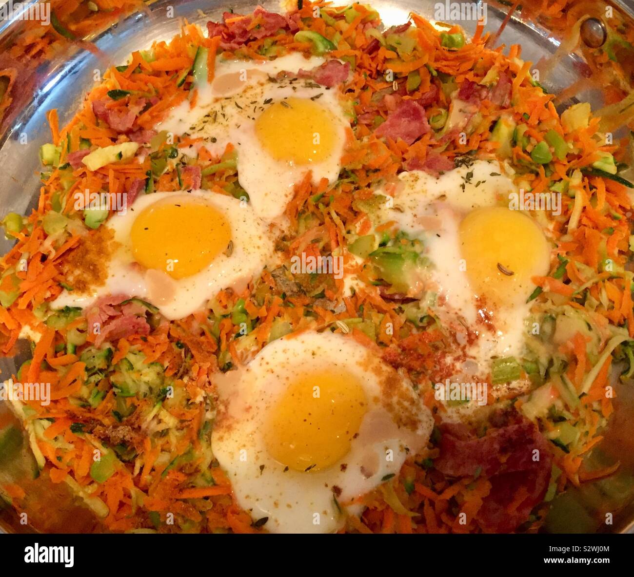 Eggs with turkey bacon and veggies in a skillet Stock Photo