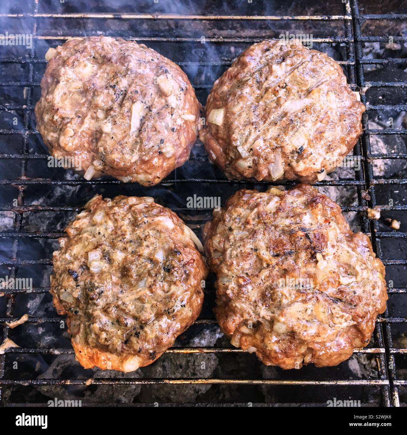 Homemade burgers cooking on a charcoal barbecue grill. - Smartphone Captured Stock Image