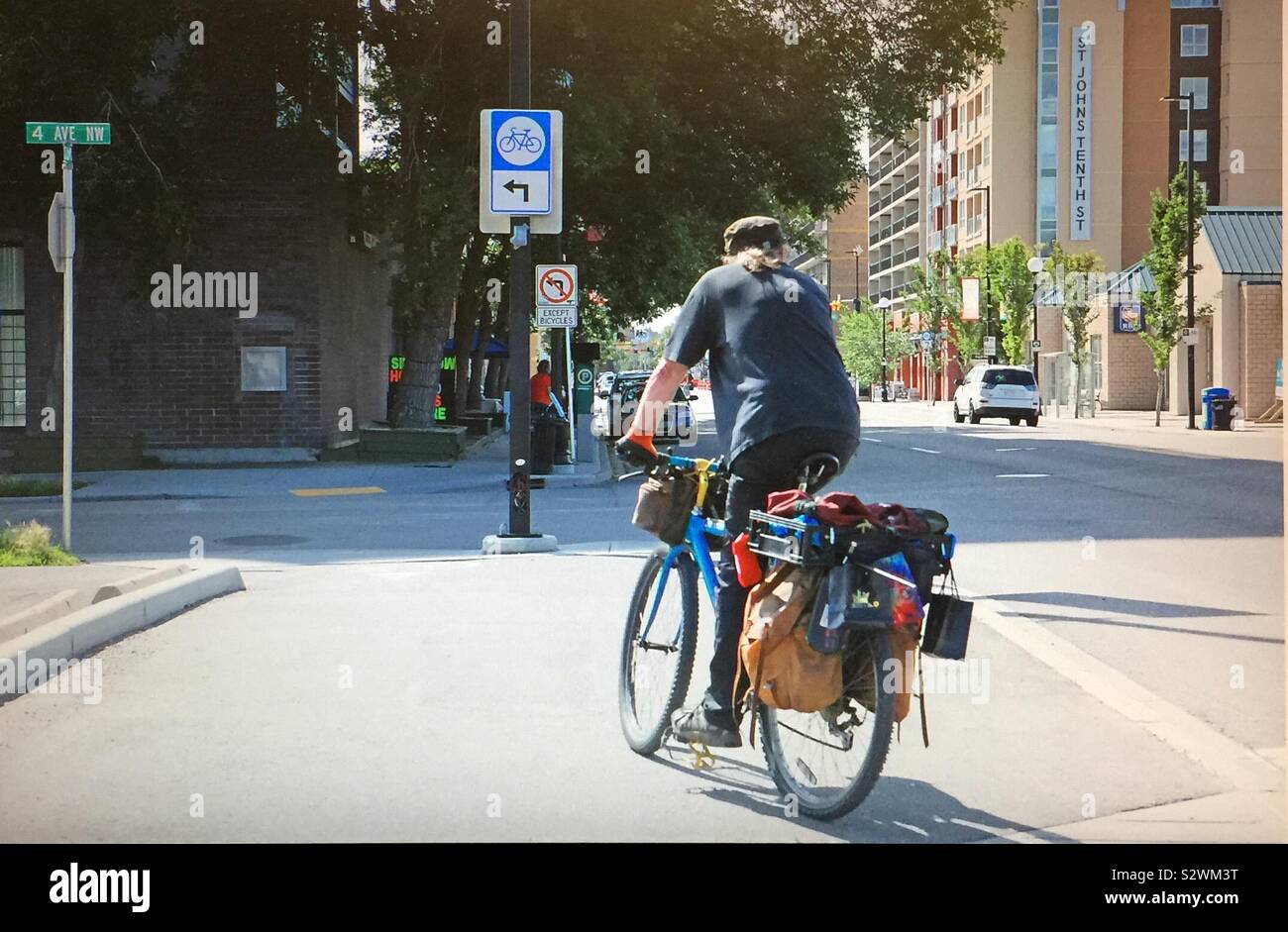 Street photography in Kensington in Calgary, Alberta, Canada,  cycler with saddlebags on his bicycle - Smartphone Captured Stock Image
