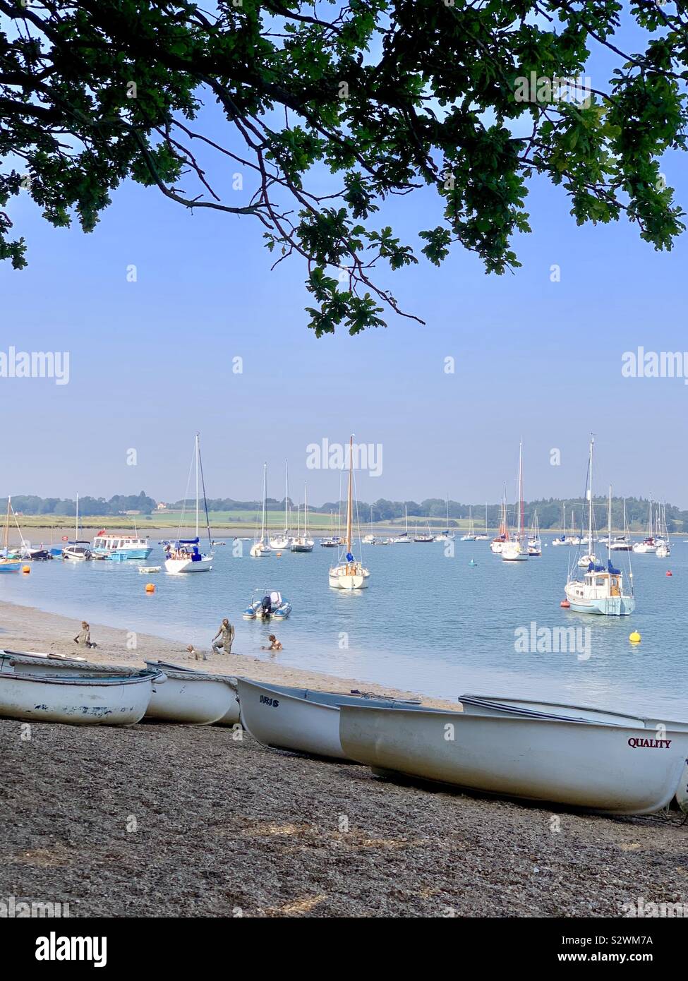 Waldringfield, Suffolk, UK - 27 August 2019: Boats on the beach and in the river and muddy teenagers on the beach. - Smartphone Captured Stock Image