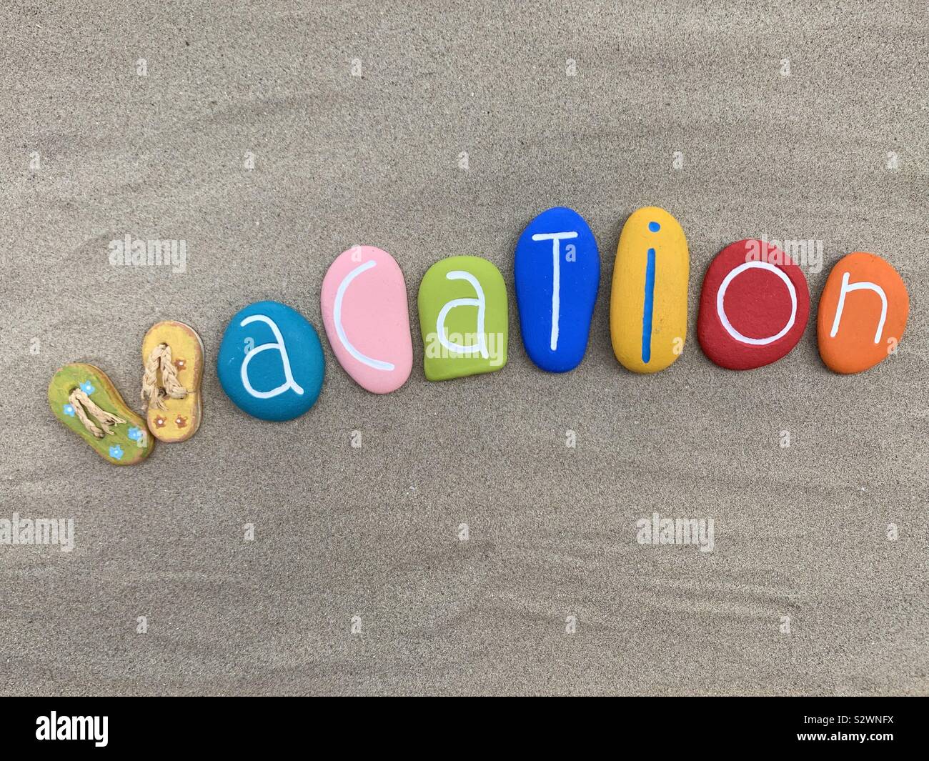 Vacation text composed with a creative handmade painted stones on the sand - Smartphone Captured Stock Image