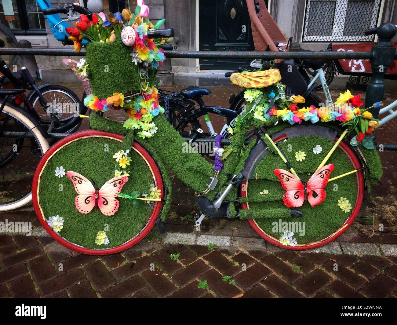 A beautifully decorated nature themed bicycle featuring fake grass, butterflies and flowers in Amsterdam, The Netherlands - Smartphone Captured Stock Image