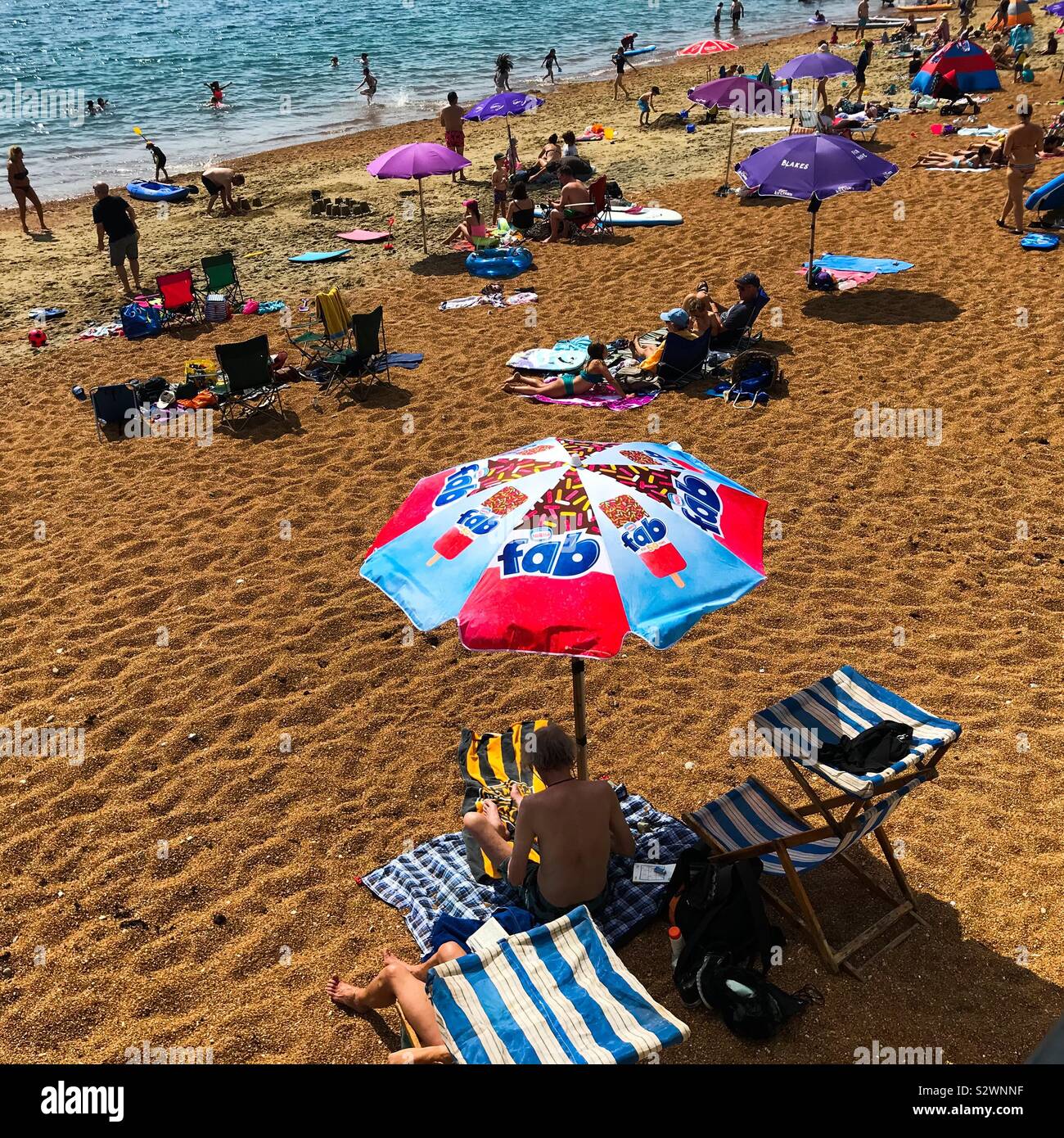 On the beach British summer scene with a colourful beach umbrella sun shade at Ventnor beach on the Isle of Wight Stock Photo