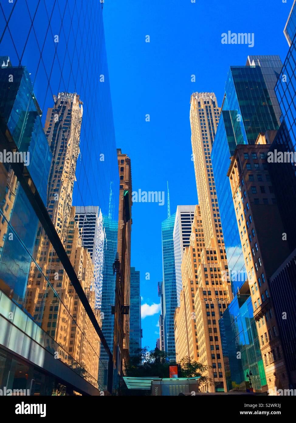 Skyscrapers and their reflections in a canyon of buildings looking west on 42nd St., Midtown Manhattan, NYC, USA - Smartphone Captured Stock Image