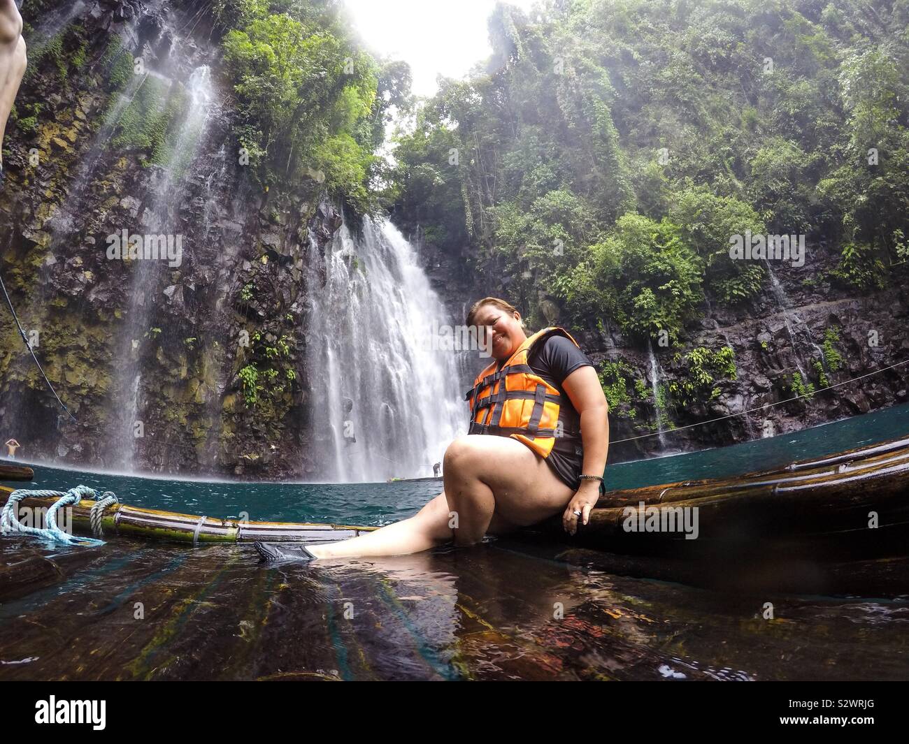A woman sits on a bamboo boat in front of Tinago Falls at Illigan City in The Philippines. - Smartphone Captured Stock Image