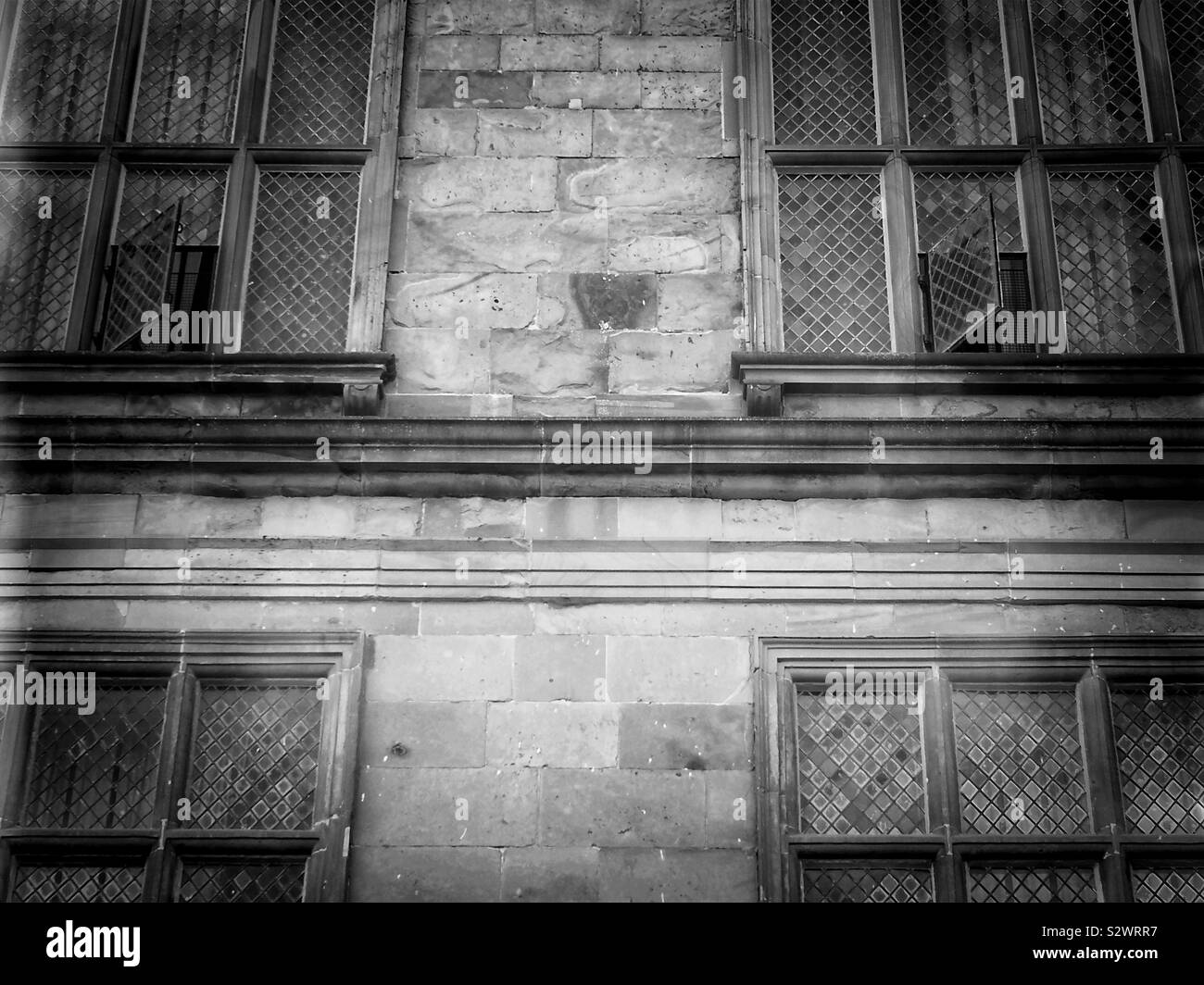 Black and white image of building facade with leaded mullioned windows - Smartphone Captured Stock Image