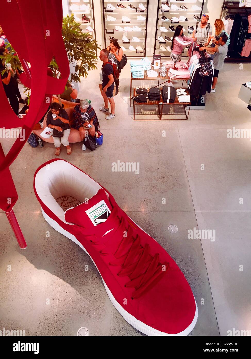 A giant display athletic shoe and shoppers on the main floor of the puma flag ship store on fifth Avenue, NYC, USA - Smartphone Captured Stock Image