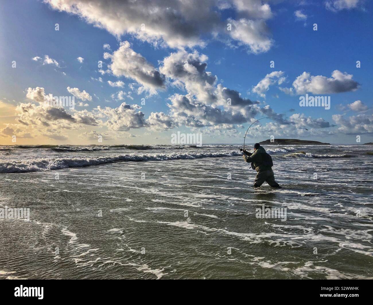 Angler casting into the surf at Llangennith beach , Gower, Swansea, South West Wales, August. Stock Photo