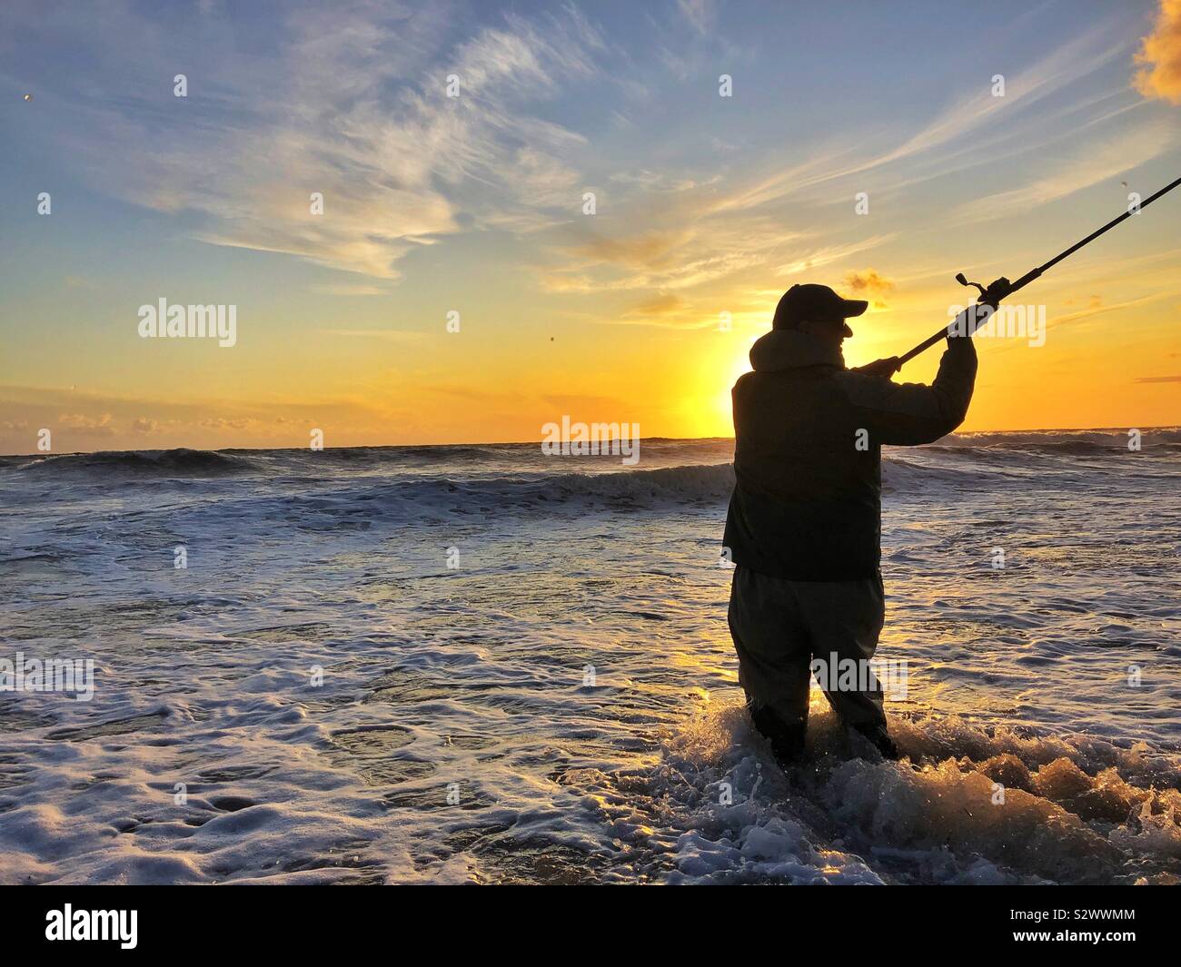Angler casting into the surf at Llangennith, Gower, Swansea, South West Wales, August. Stock Photo