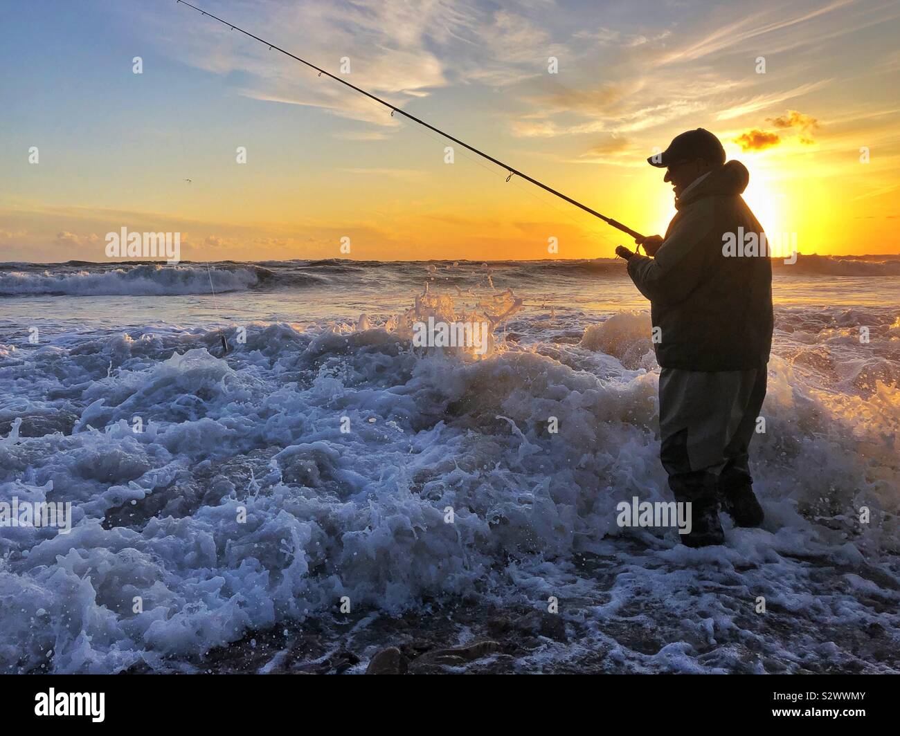 Angler fishing in surf at sunset on Llangennith beach, Gower, Swansea, South West Wales, August. - Smartphone Captured Stock Image