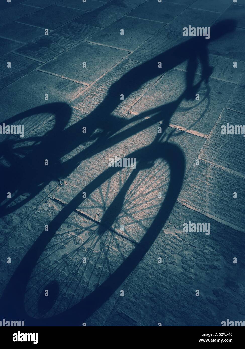The atmospheric and possibly sinister shadows of a boy and his bicycle. Photo Credit - © COLIN HOSKINS. - Smartphone Captured Stock Image