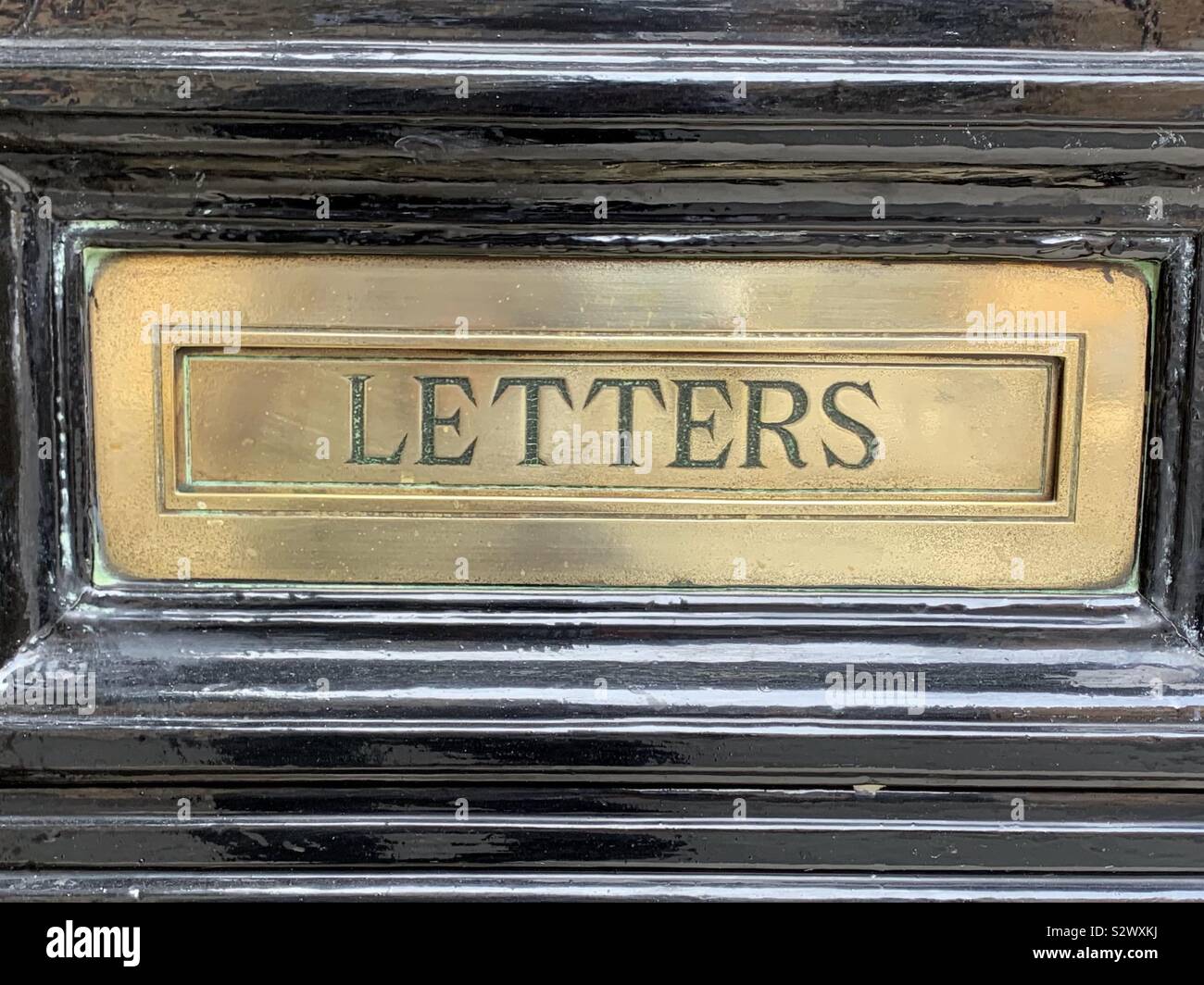 Post box or letterbox stating letter.  Brass finish mail post and postage - Smartphone Captured Stock Image
