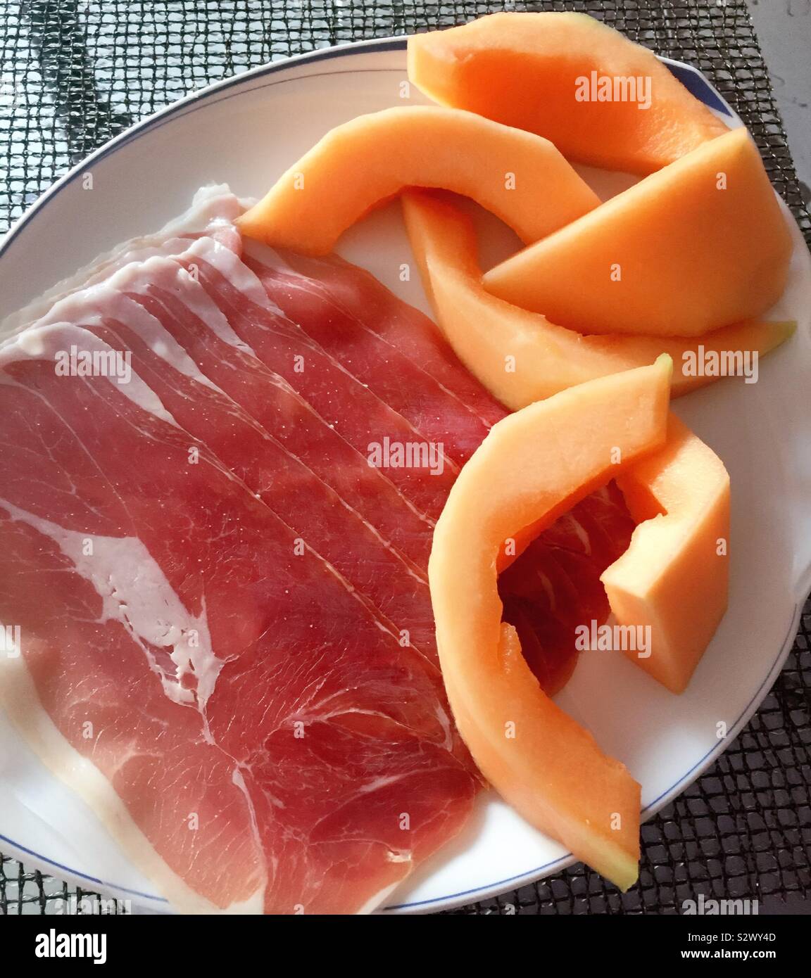 Flat play close up of a gourmet presentation of fresh cantaloupe and prosciutto - Smartphone Captured Stock Image