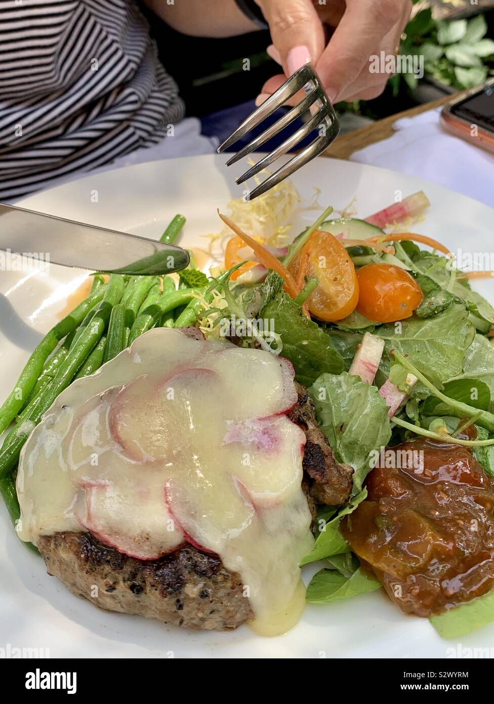 Keto burger with salad and no bun. Topped with sliced radishes and melted cheese. Stock Photo