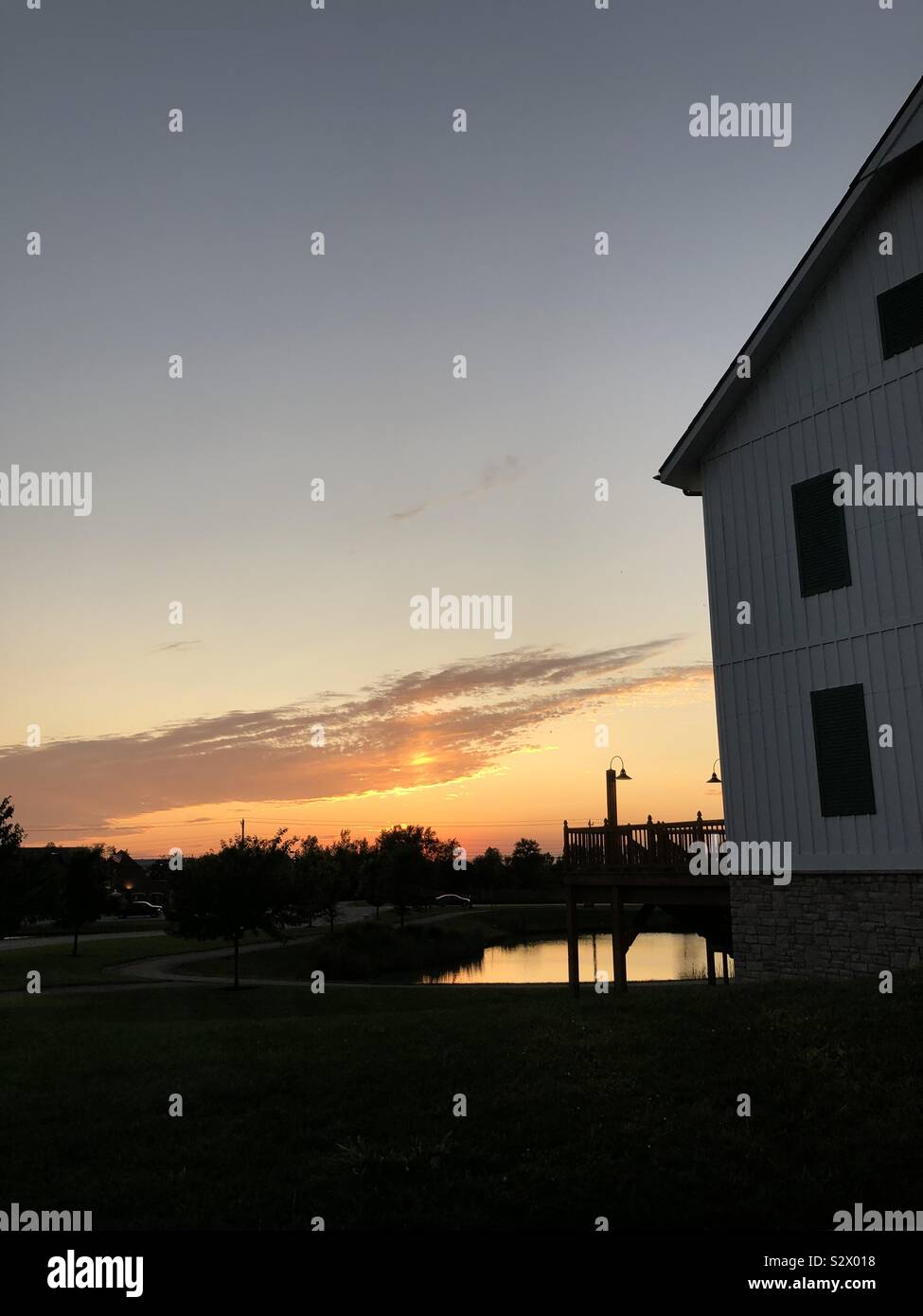 A partial view of a barn with the sun setting in the background. - Smartphone Captured Stock Image