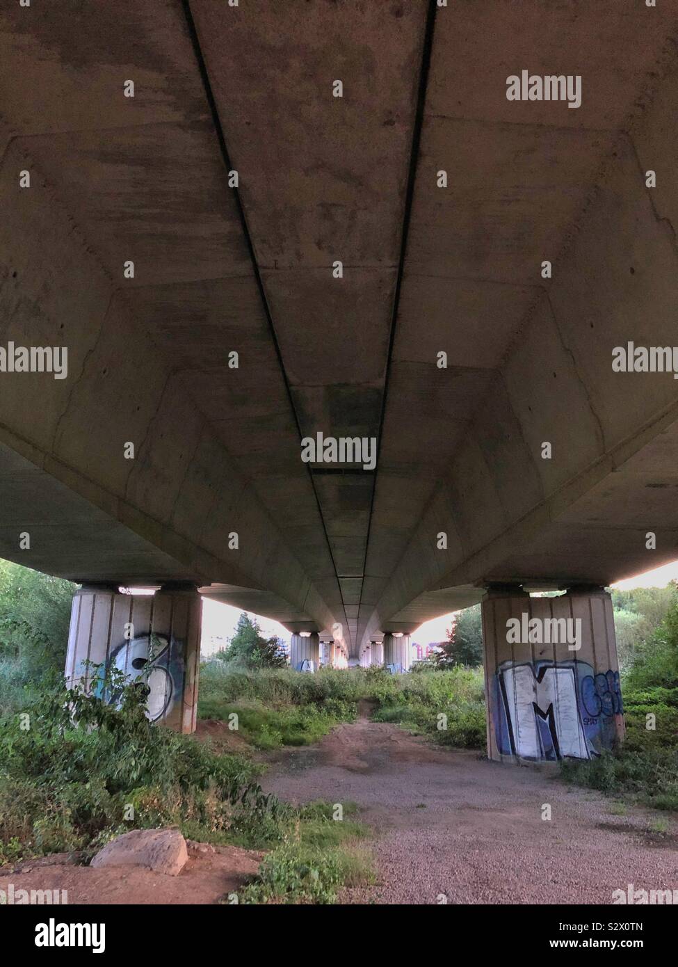 Underneath a road bridge with graffitied support columns. - Smartphone Captured Stock Image