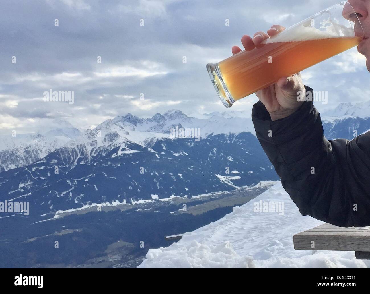 Man drinking lager on a snowy mountain - Smartphone Captured Stock Image