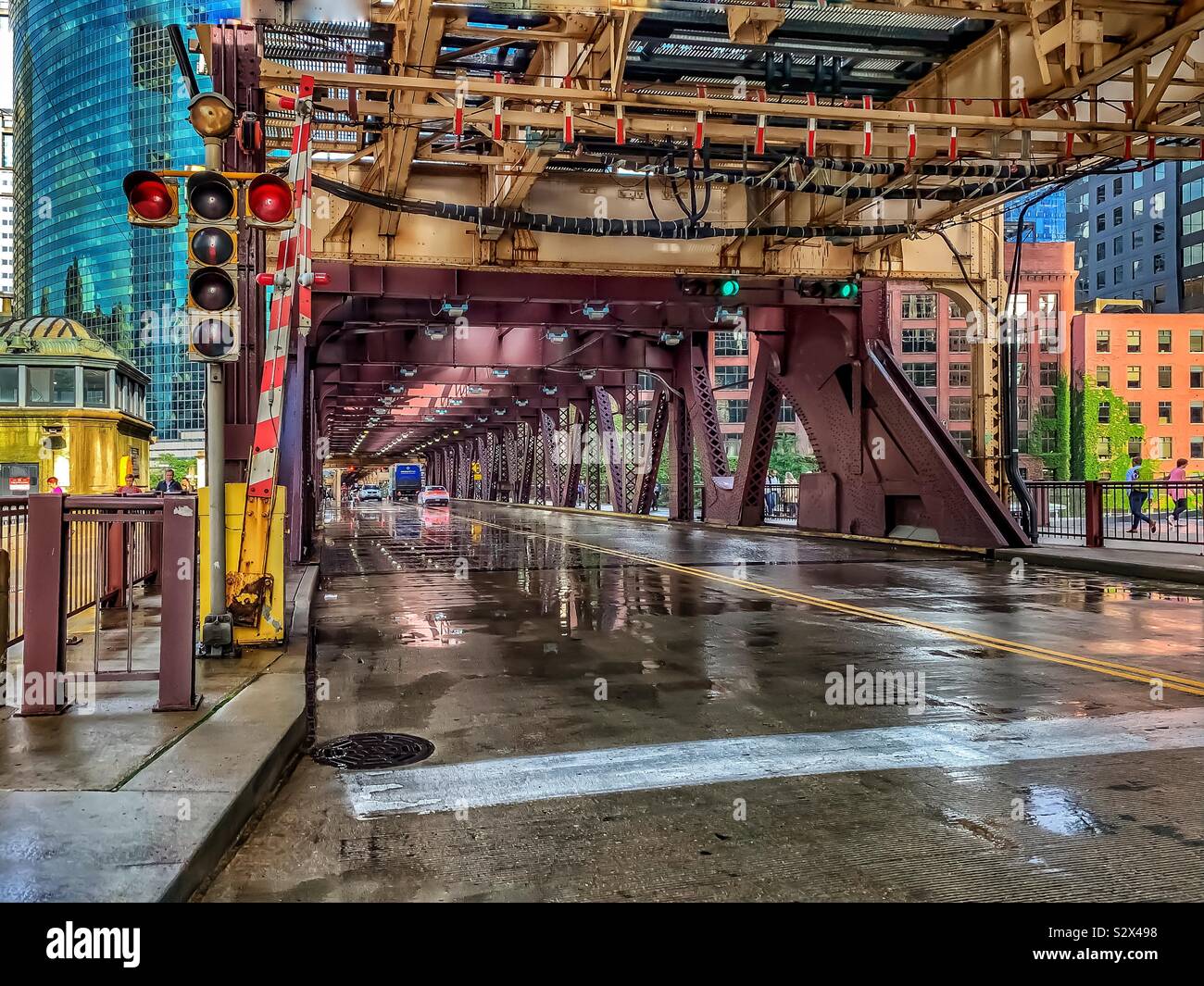 View of Lake Street bridge under elevated “el” tracks, in Chicago Loop after rainstorm with wet pavement on summer afternoon. Stock Photo