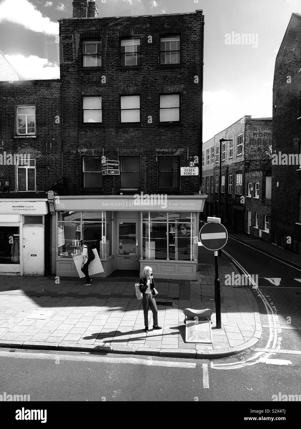 Woman standing on a corner of the street near Angel London - Smartphone Captured Stock Image