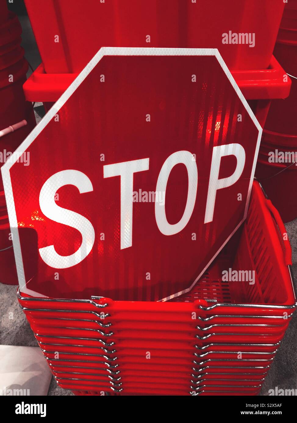 Stop sign displayed in a stack of plastic shopping baskets in a store, USA - Smartphone Captured Stock Image