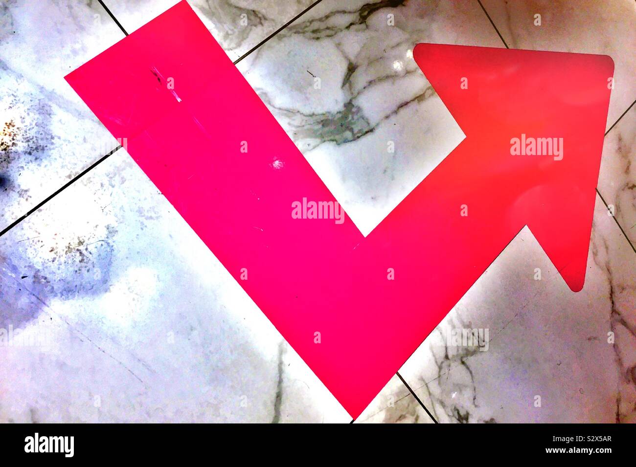 Bold red stylized arrow painted on a floor - Smartphone Captured Stock Image