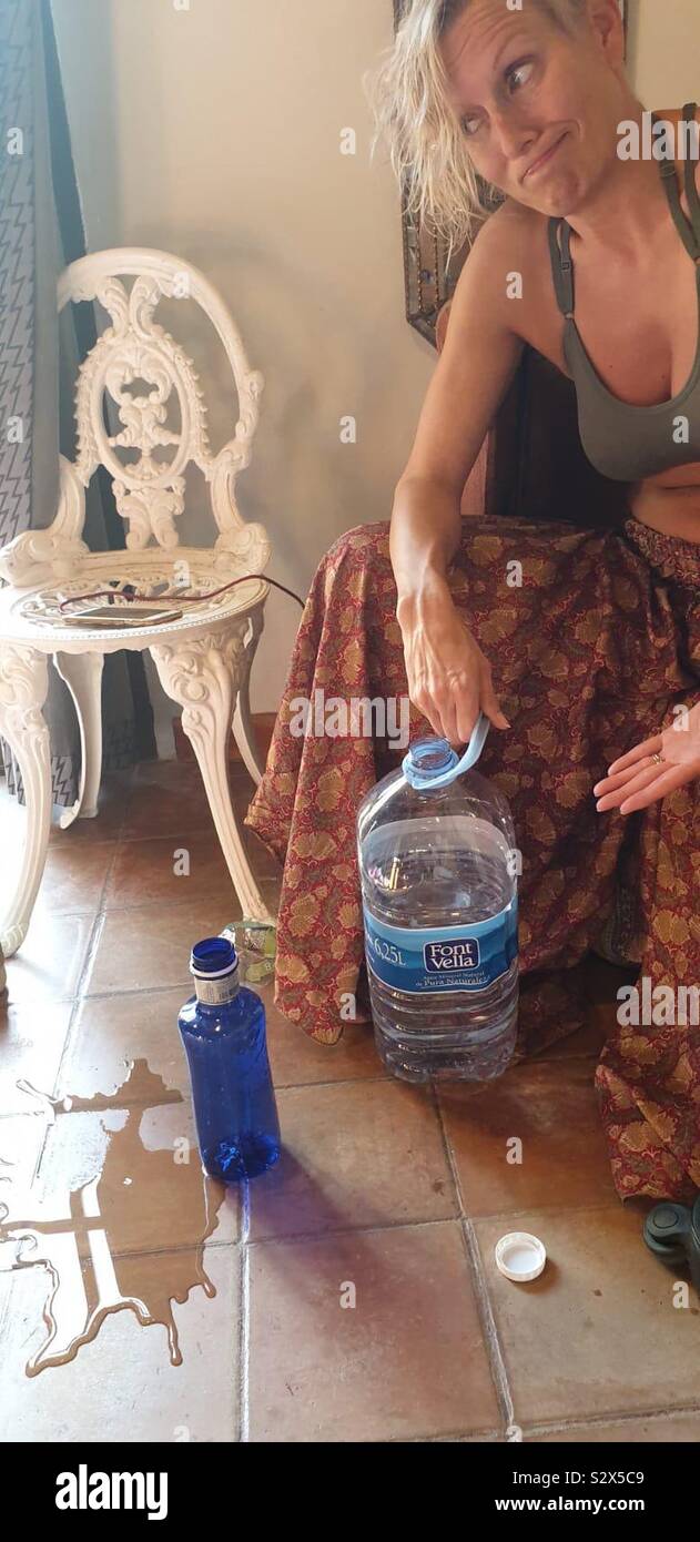 Woman pulling silly face next to spilt water - Smartphone Captured Stock Image