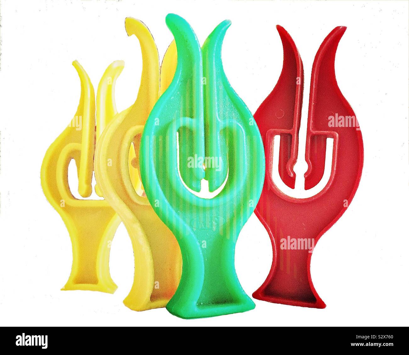 Four colourful plastic clothes pegs standing up in a group. The pegs at this angle look as if they are smiling Stock Photo