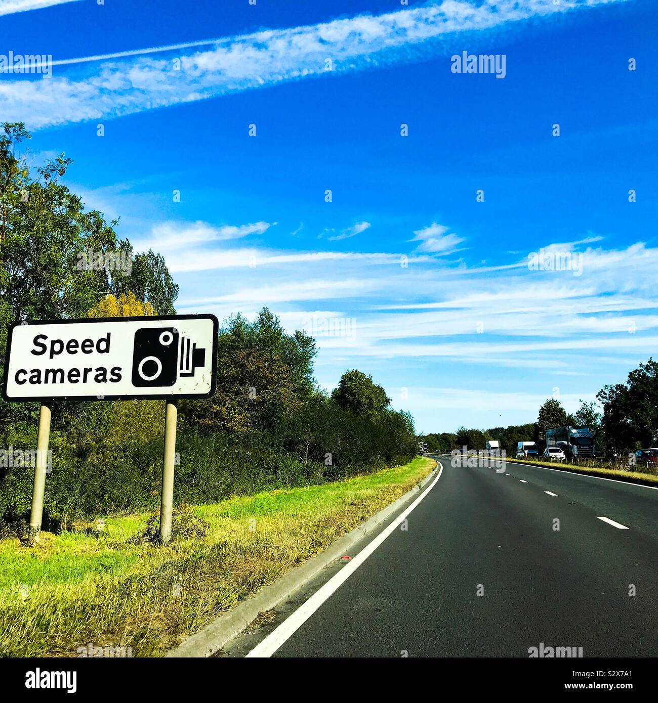 A speed cameras warning sign on the grass verge side of a dual carriageway road in the UK Stock Photo
