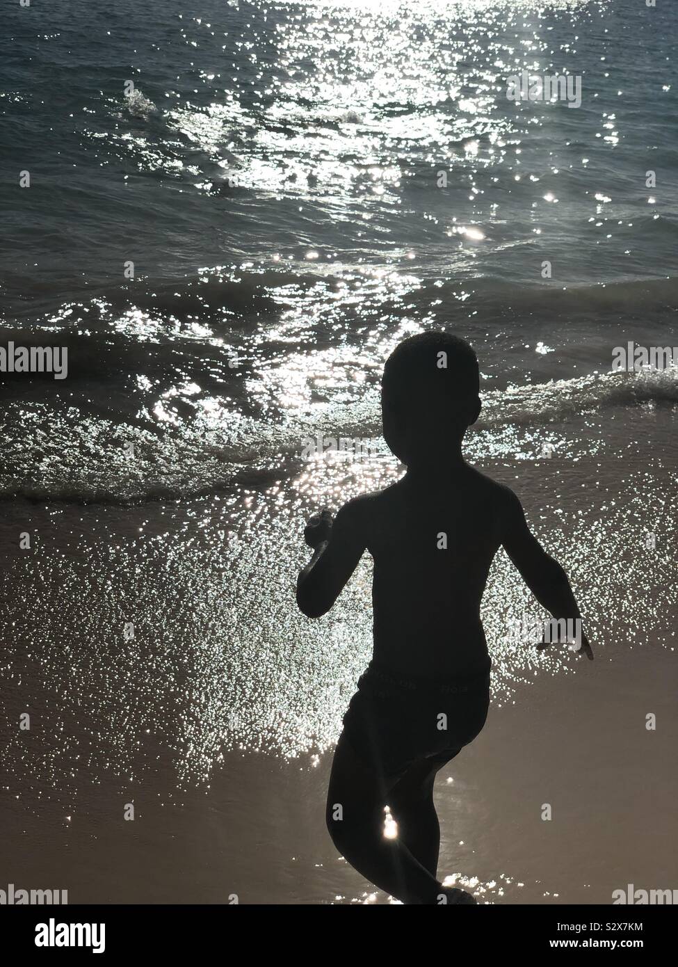 A little boy running into the Caribbean ocean Stock Photo
