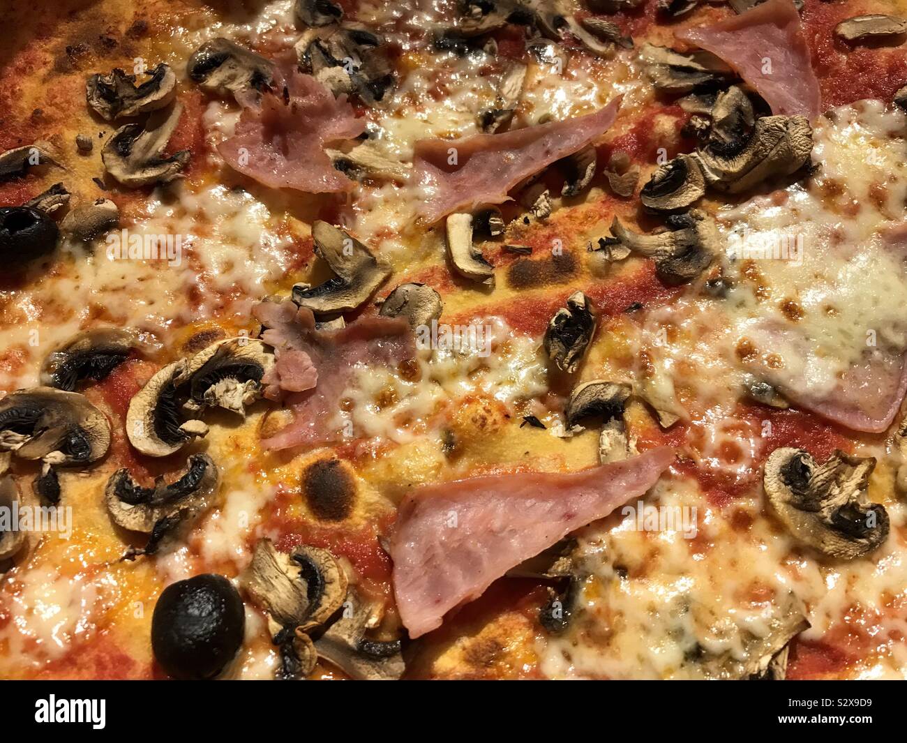 Close up view of a pizza with ham, cheese, mushroom and olives. - Smartphone Captured Stock Image