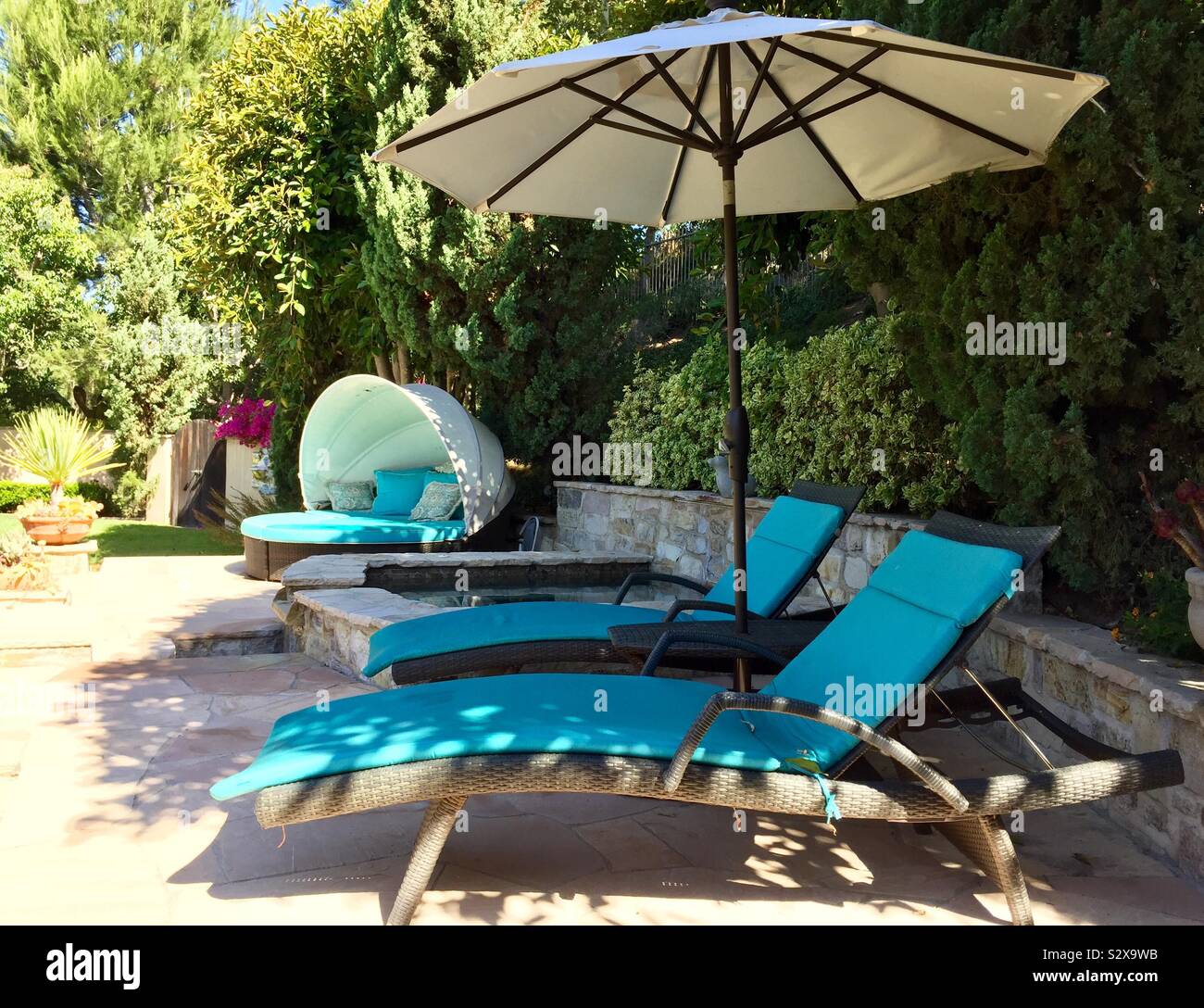 Chaise lounge chairs with umbrella by the pool Stock Photo