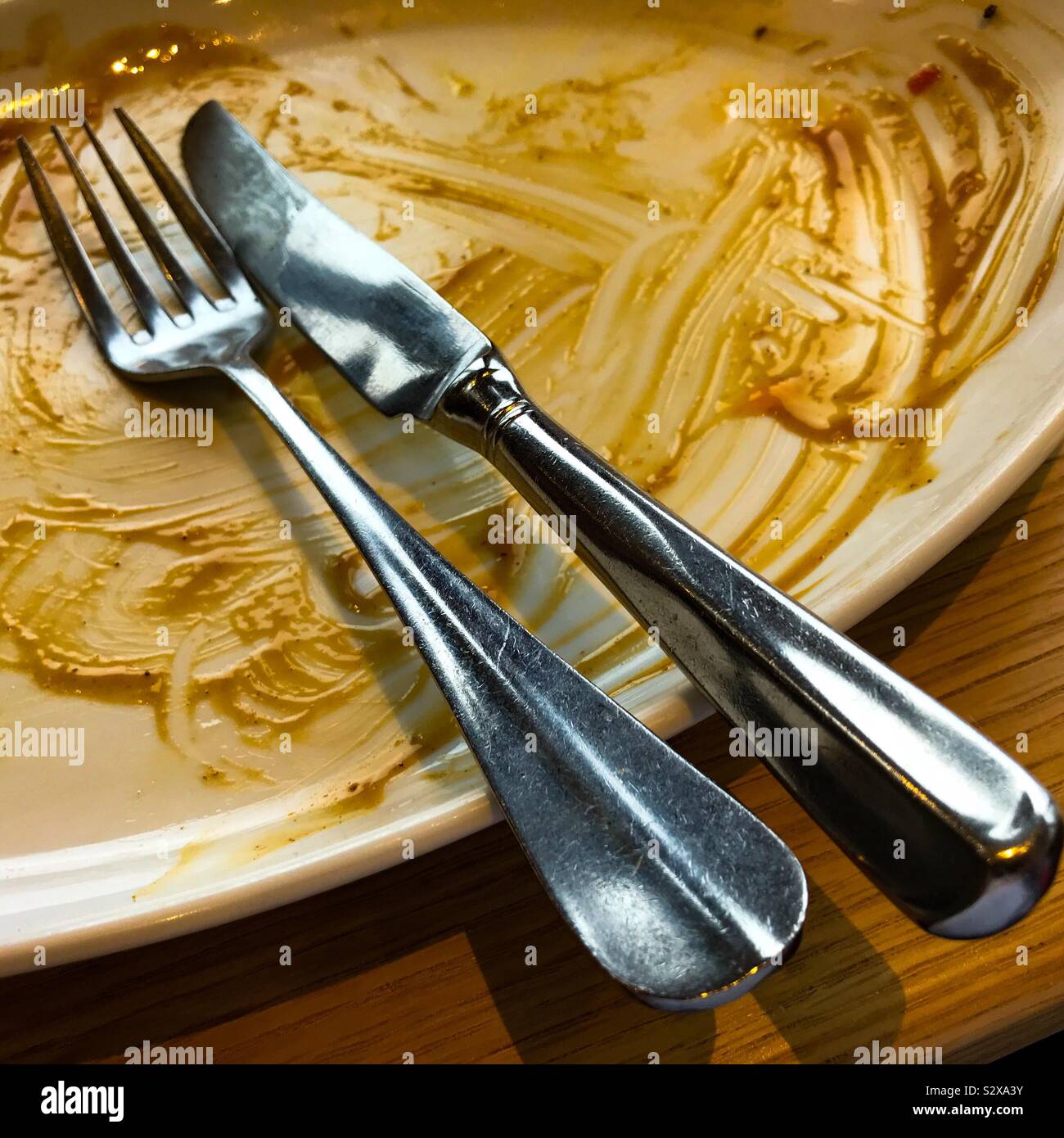 A finished eating empty plate with knife and fork placed on it Stock Photo