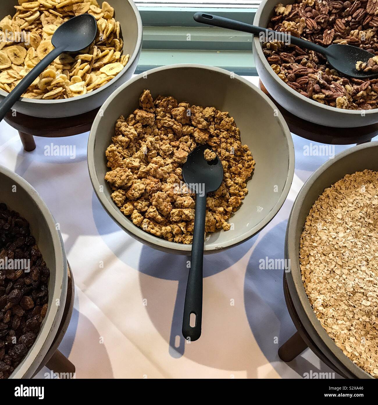 Various cereals in serving bowls on servery counter top in hotel breakfast room for guests to help themselves Stock Photo