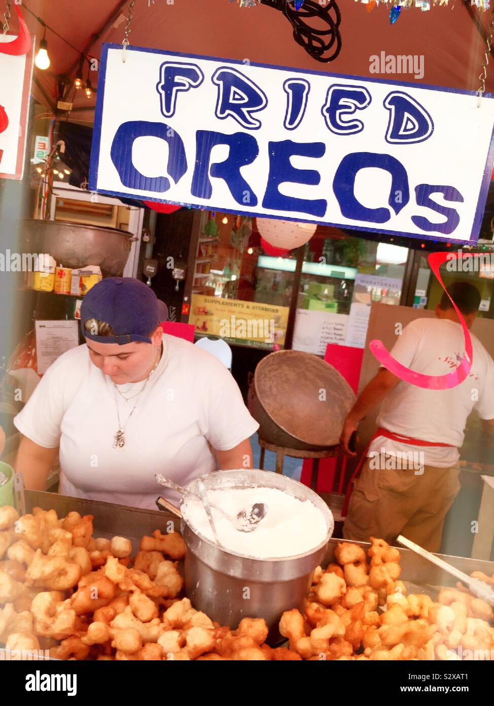 Workers in a food stall selling fried Oreos on Mulberry Street during the feast of San Gennaro, Little Italy, NYC, USA - Smartphone Captured Stock Image