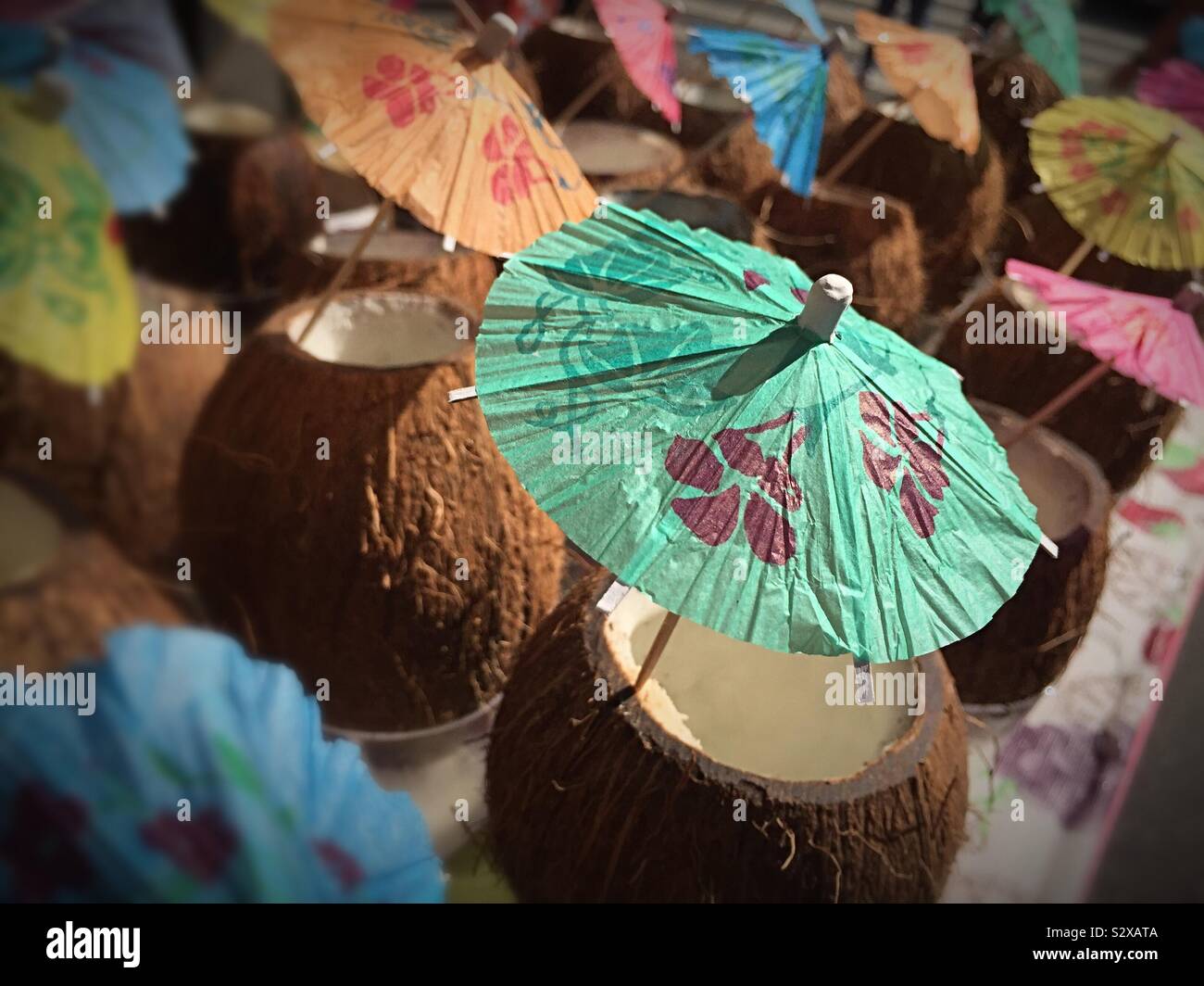 Tropical tiki bar cocktails served in a coconut shell with tiny decorative umbrellas, Little Italy, NYC, USA - Smartphone Captured Stock Image