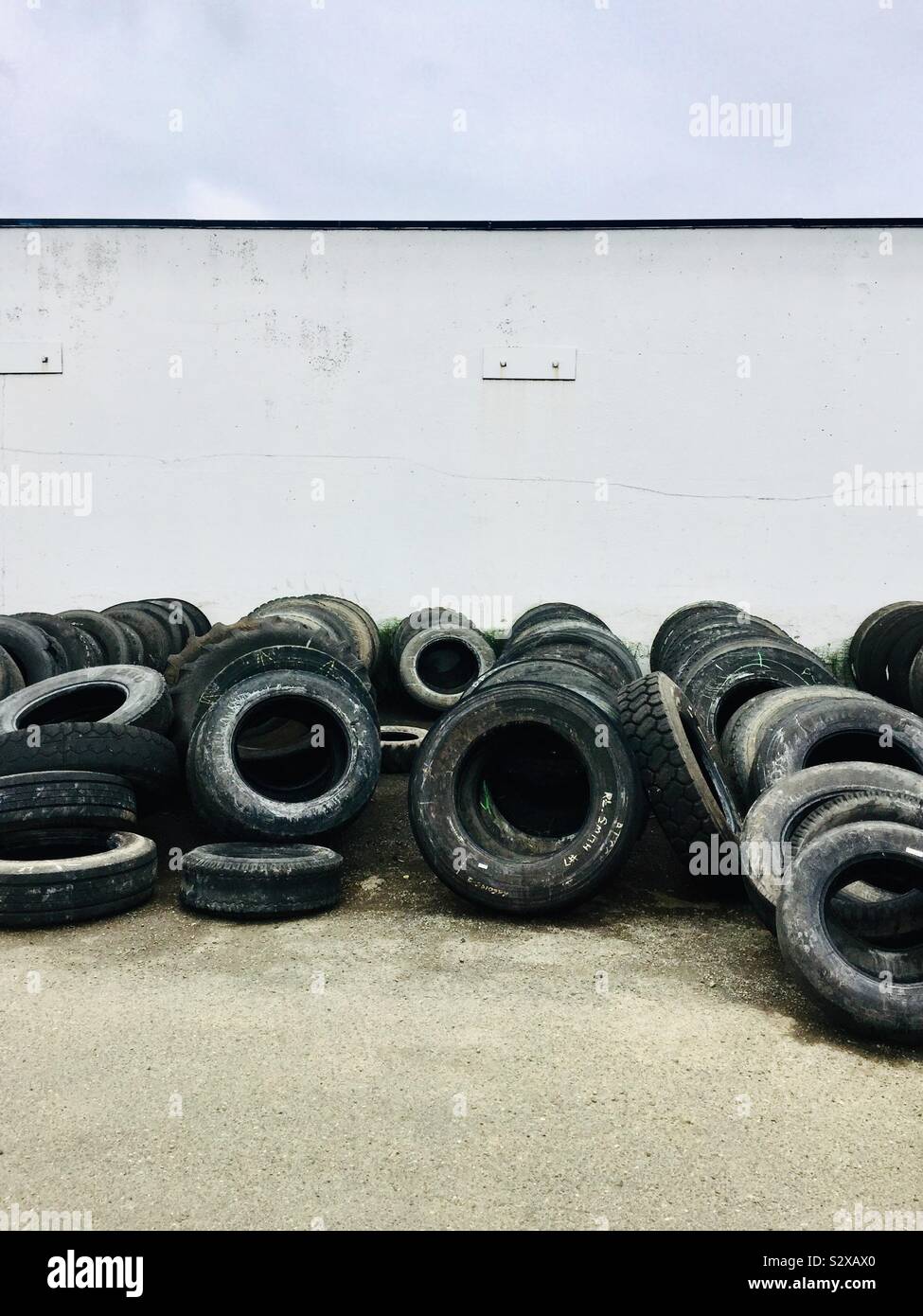 Used tires stacked against a wall waiting to be recycled Stock Photo